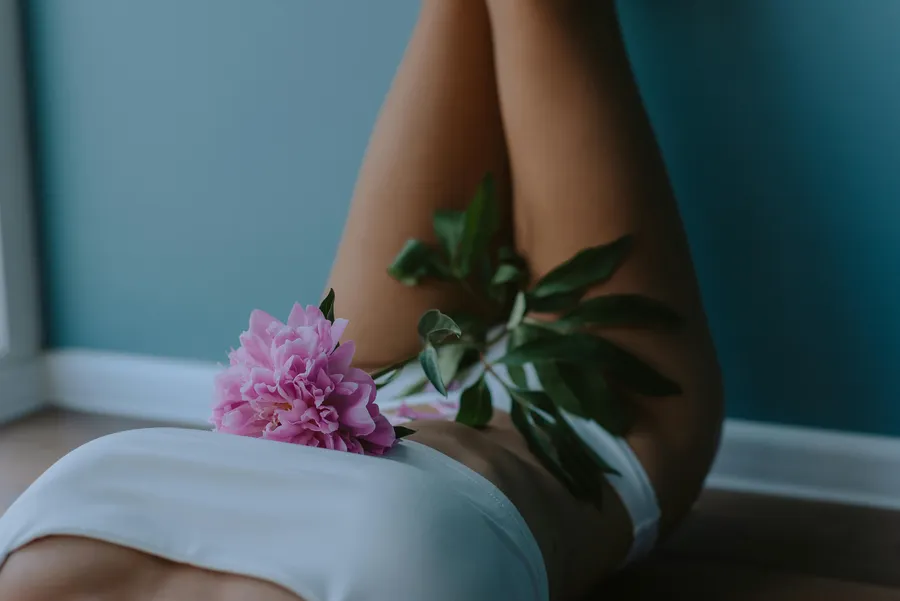 Pivoine posé sur le buste d'une femme allongée avec les jambes appuyées contre un mur
